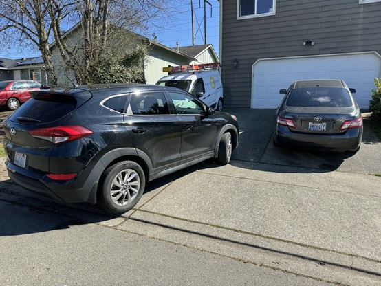 A black SUV is parked across the sidewalk and into the road, despite ample space in the house's driveway should the driver have wished to park the vehicle in a non-obstructive, legal manner.