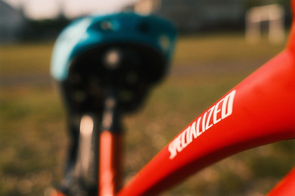 A close-up of a red Specialized bicycle on grass, with a teal bicycle helmet in the background.