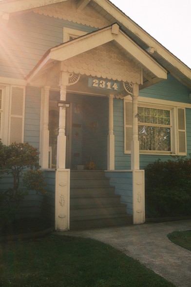 The front porch of a residential house with columns and scalloped trim, with the house number "2314" displayed above the front door.